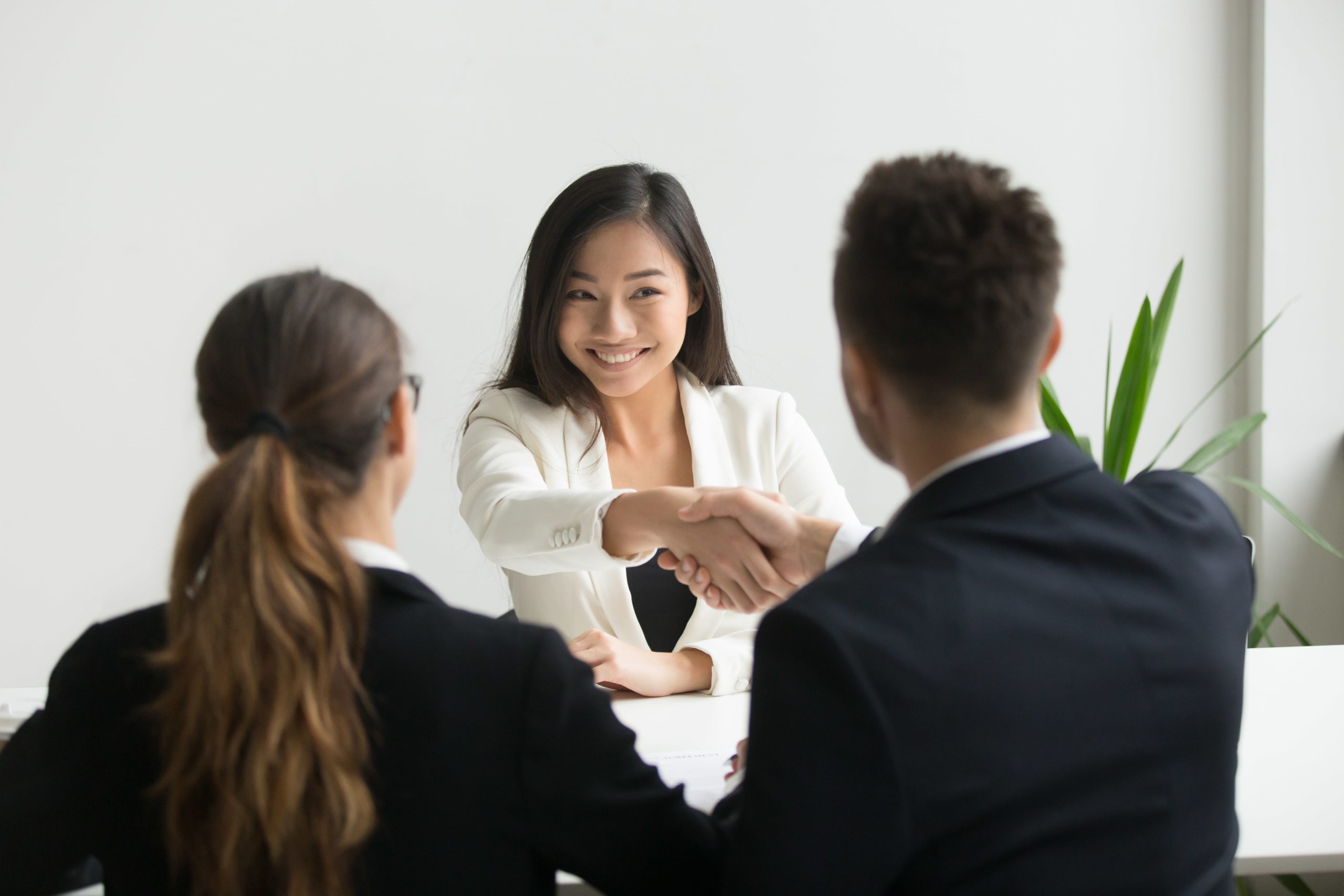 Photo of a couple of interviewrs closing a deal with a women. The man is shaking the women's hand