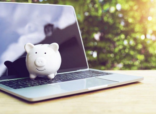 Photo of an open laptop with a white piggybank on top